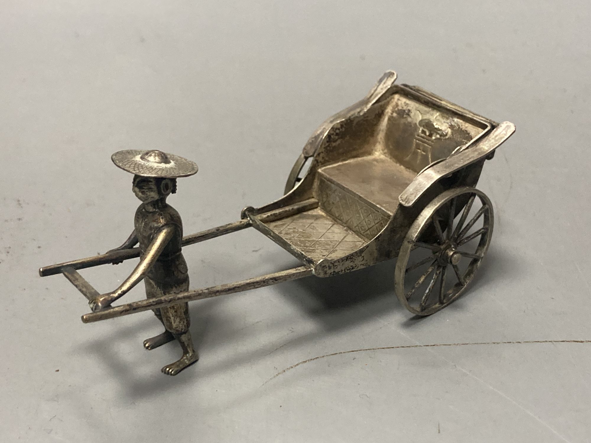 A group of Chinese white metal models of a sampan by Wang Hing, rickshaw and sedan chair etc.